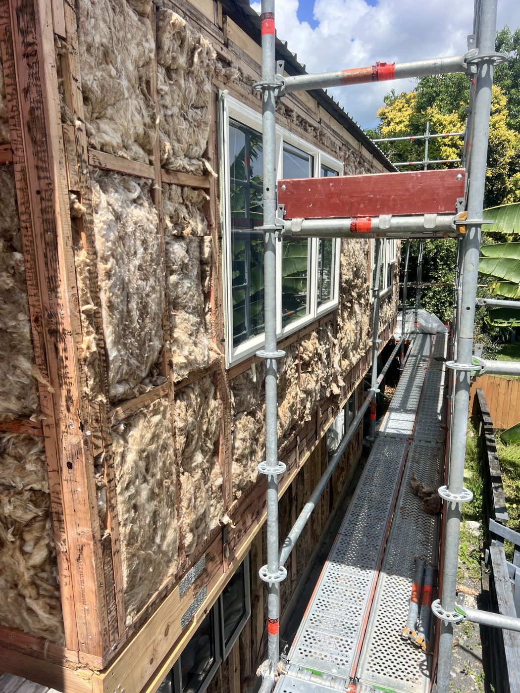Old cladding stripped back to the framing, with scaffolding up