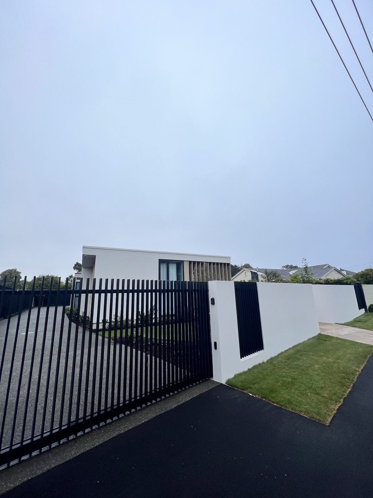 Plastered front wall with black slatted gate and fence panels