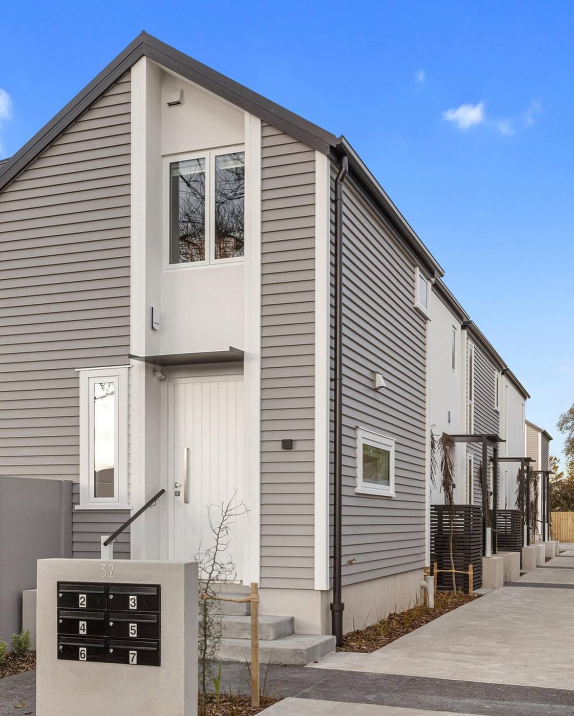 Completed townhouses with grey weatherboards, white plaster and black joinery