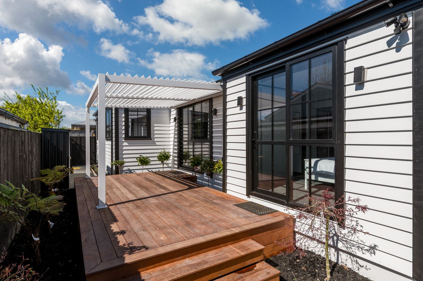 Completed new build with white weatherboards, black joinery and hardwood deck, Christchurch