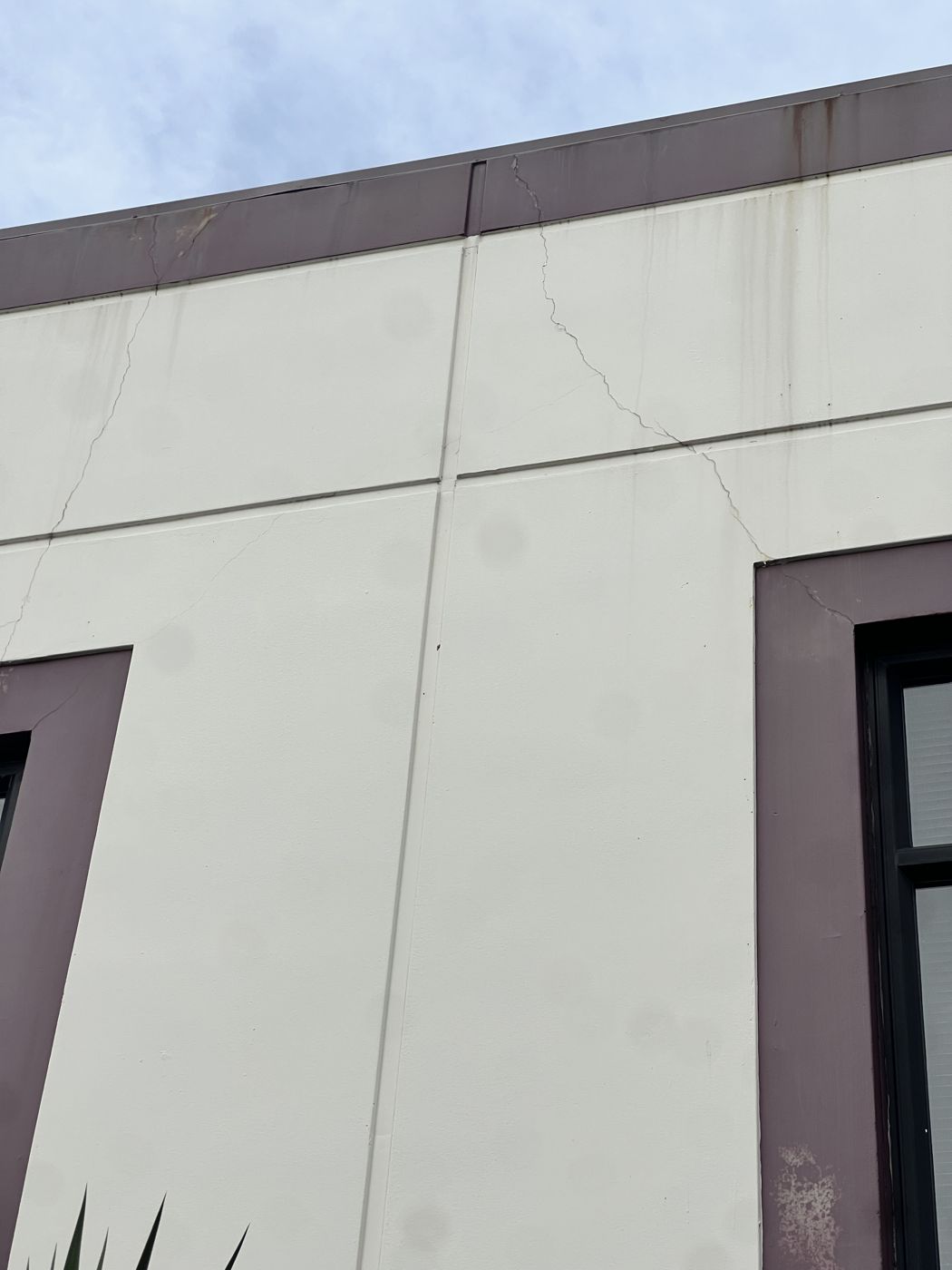 Cracked plaster cladding on a commercial building before repair